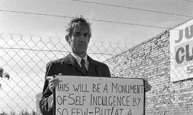 Cr Salter standing with a protest placard [picture].