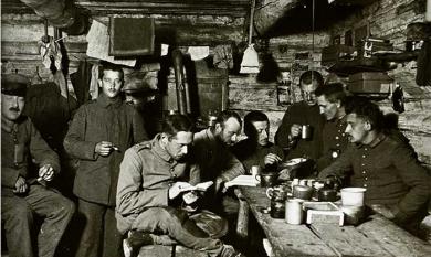 German soldier WW1, Erwin reading book in foreground, in living quarters with other soldiers, 1917 [picture].