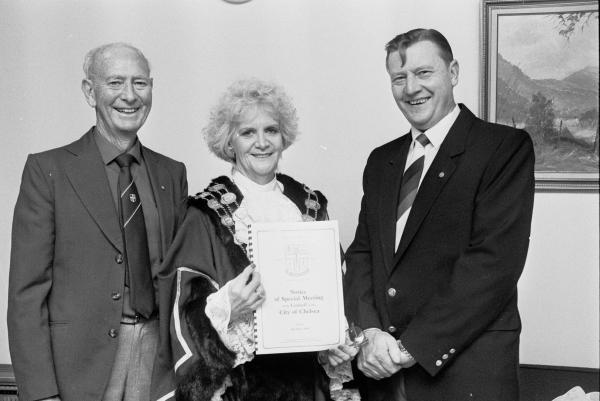 Mr Frank McGuire, Chelsea historian and secretary of the Chelsea Historical Society, Chelsea Mayor Cr Marie McIntosh and Mr John Banechteld President of Chelsea Historical Society, display a notice of a special meeting held to commemorate the 60th Anniversary of the City of Chelsea.  16 May 1989 [picture].