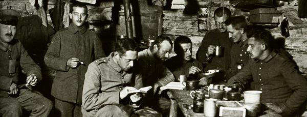 Erwin reading book in foreground, in living quarters with other soldiers, 1917