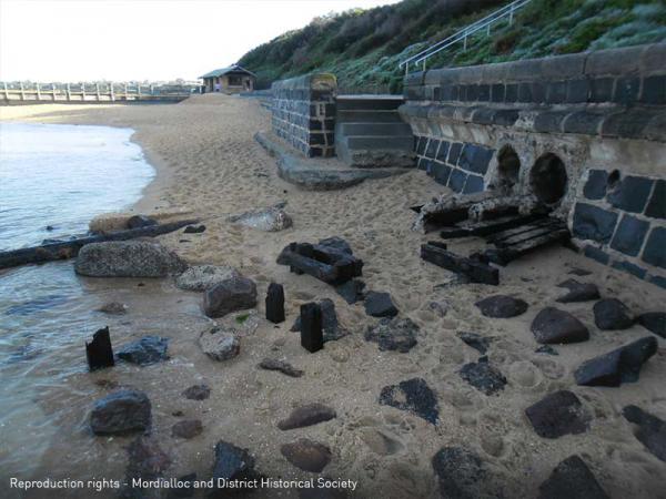 Mentone Beach showing remains of wooden rails protruding from beach wall [picture].